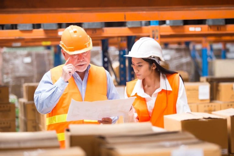 Workers reviewing plans in warehouse.