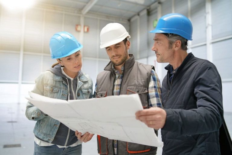 Three workers discussing a blueprint.
